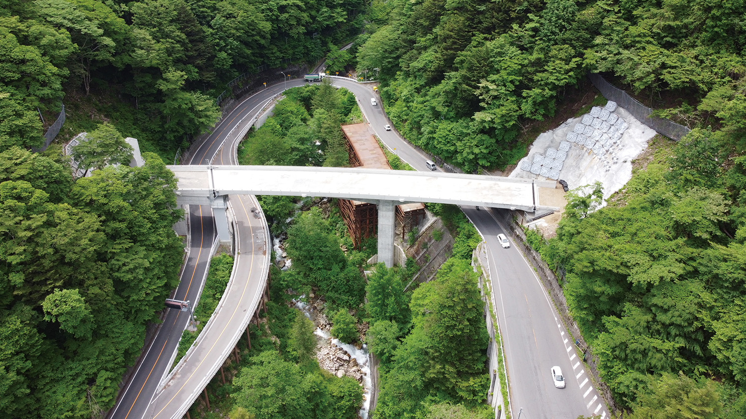 橋梁全景：左が大白川トンネル、右が新入山トンネル 中央を流れる大白川の両岸を走り急カーブしているのが現道（国道158号）